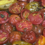 Sliced heirloom tomatoes roasting on a sheet pan