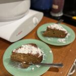 Two slices of spiced ginger cake dusted with powdered sugar on green plates