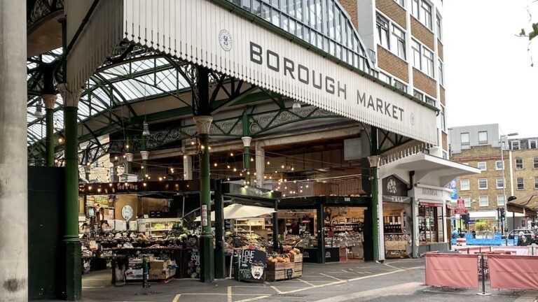 The green ironwork entrance to Borough Market in London with produce stalls visible inside