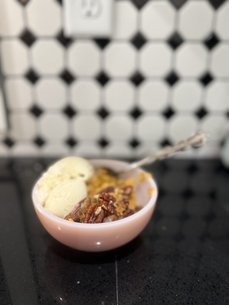 Bowl of crockpot pumpkin crunch cake topped with ice cream