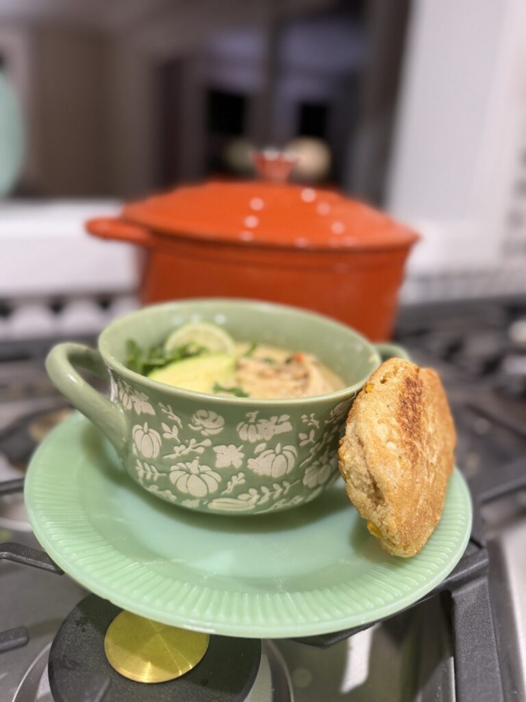 Bowl of white chicken chili with a roll on the side