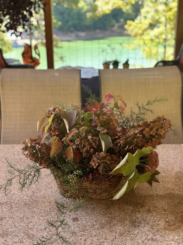 Natural fall flower arrangement of dried seed heads and greenery in a woven basket