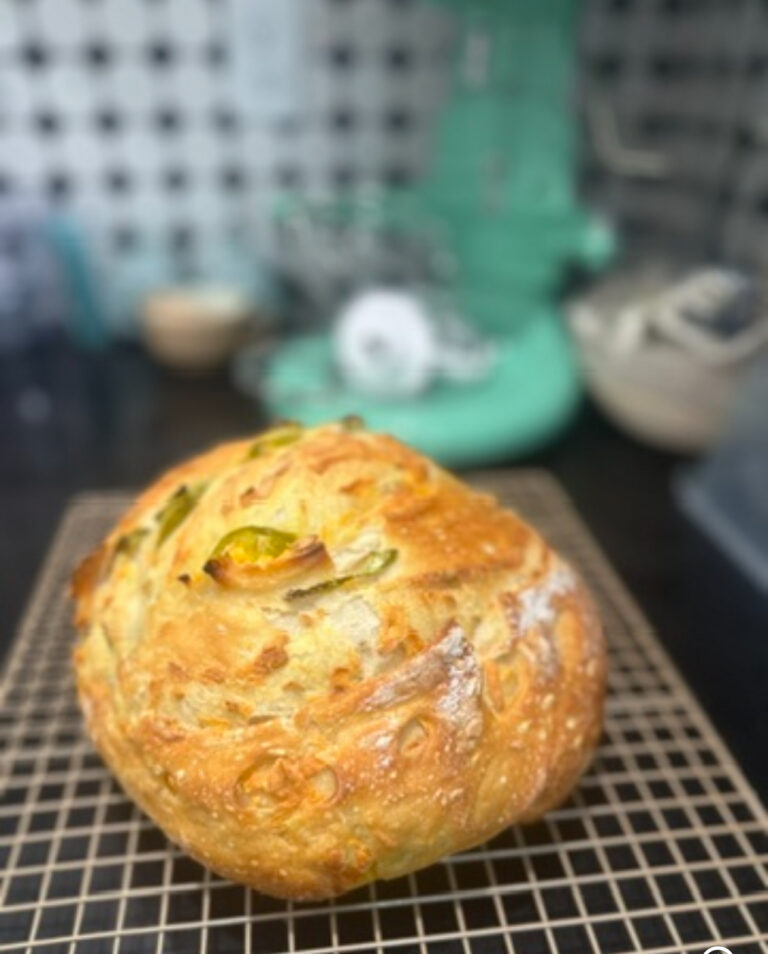 Round jalapeno studded sourdough loaf cooling on a rack by the stand mixer