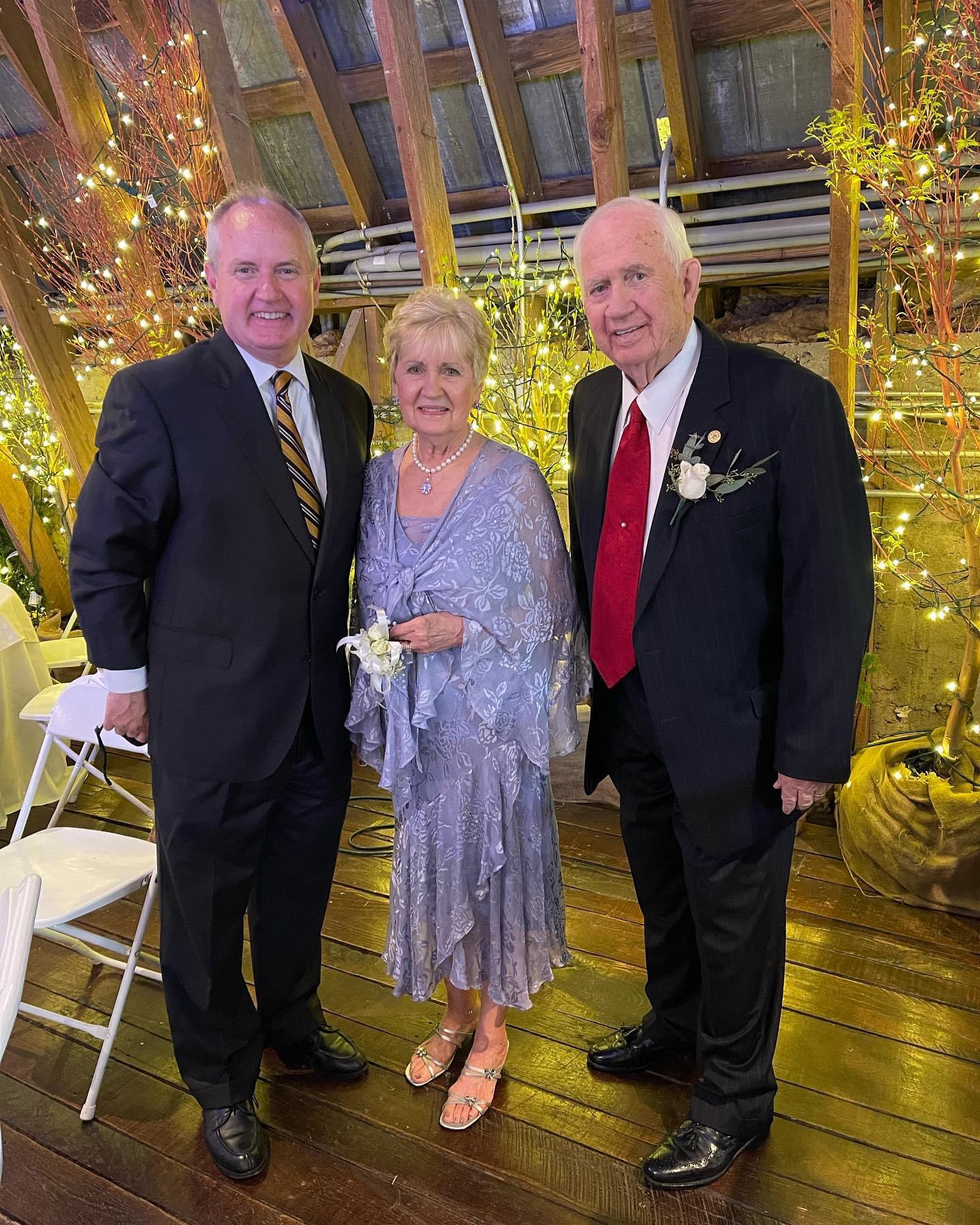Three people dressed up together at a formal celebration