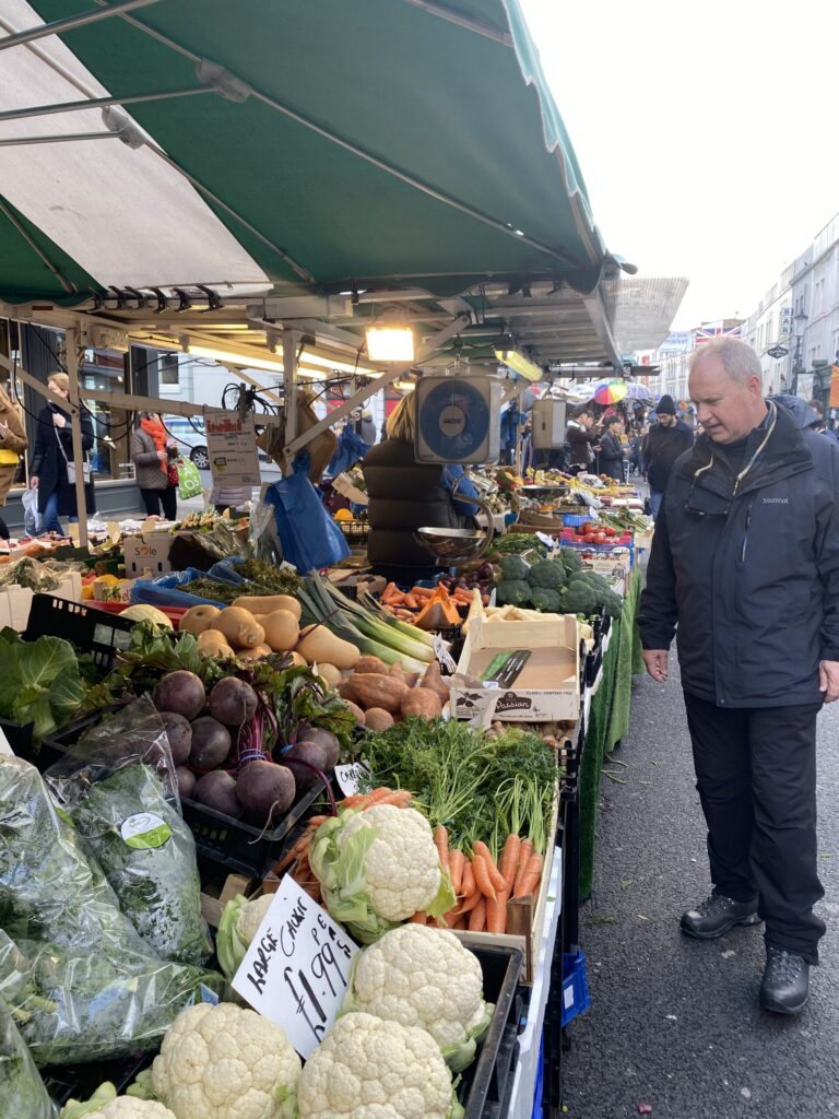 Lane Morris looking over cauliflower, carrots, beets and squash at an outdoor London greengrocer stall