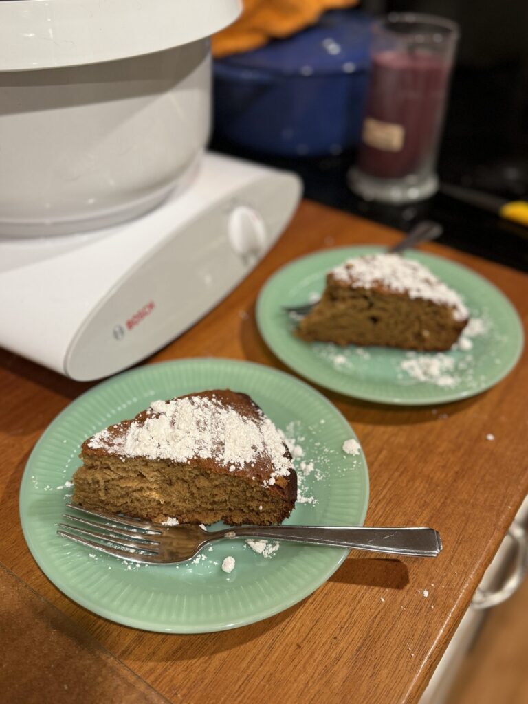 Two slices of spiced ginger cake dusted with powdered sugar on green plates