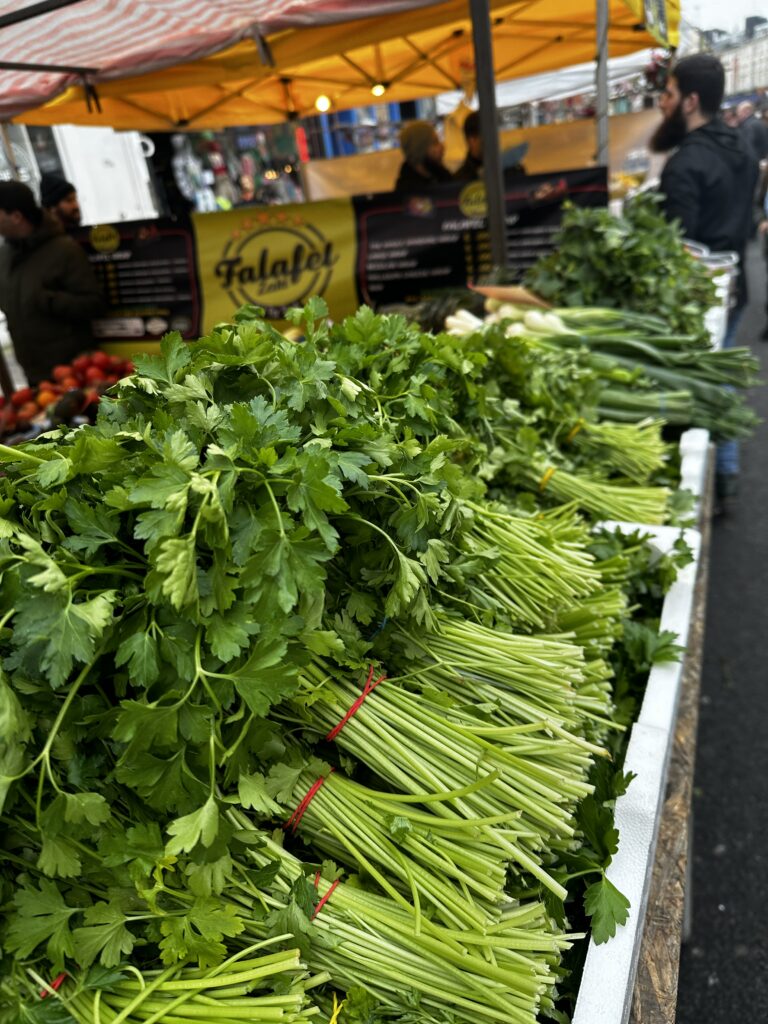 Large bunches of flat-leaf Italian parsley tied with string on a market stall