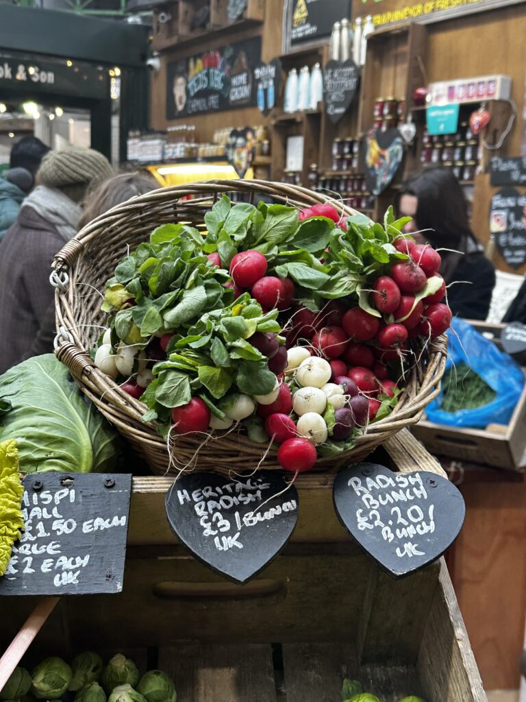Wicker basket of red, white and purple heritage radishes with hand lettered slate price signs