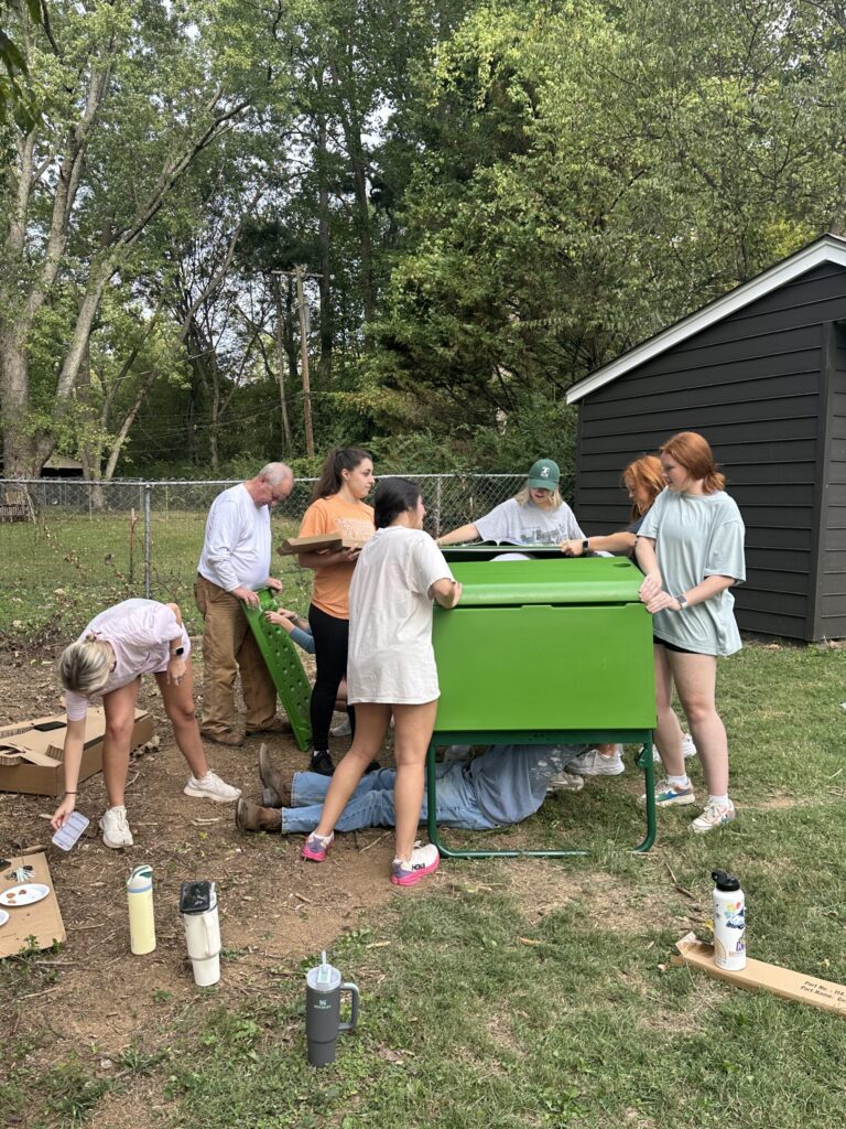 Family and friends gathered around an outdoor pizza oven beside the chicken coop