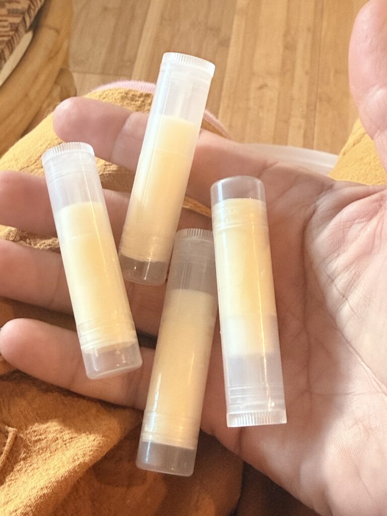 Hand holding homemade lip balm tubes