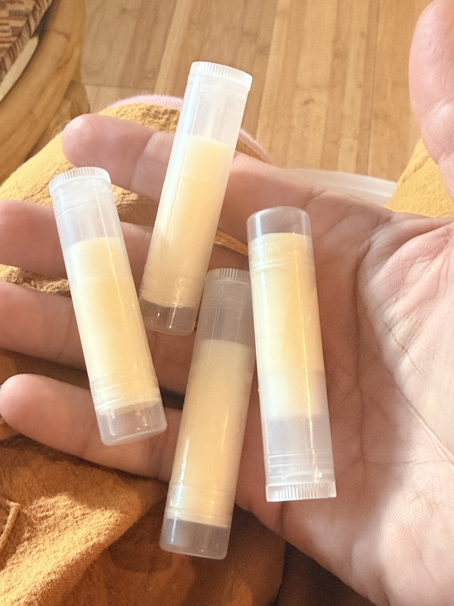 Hand holding homemade lip balm tubes