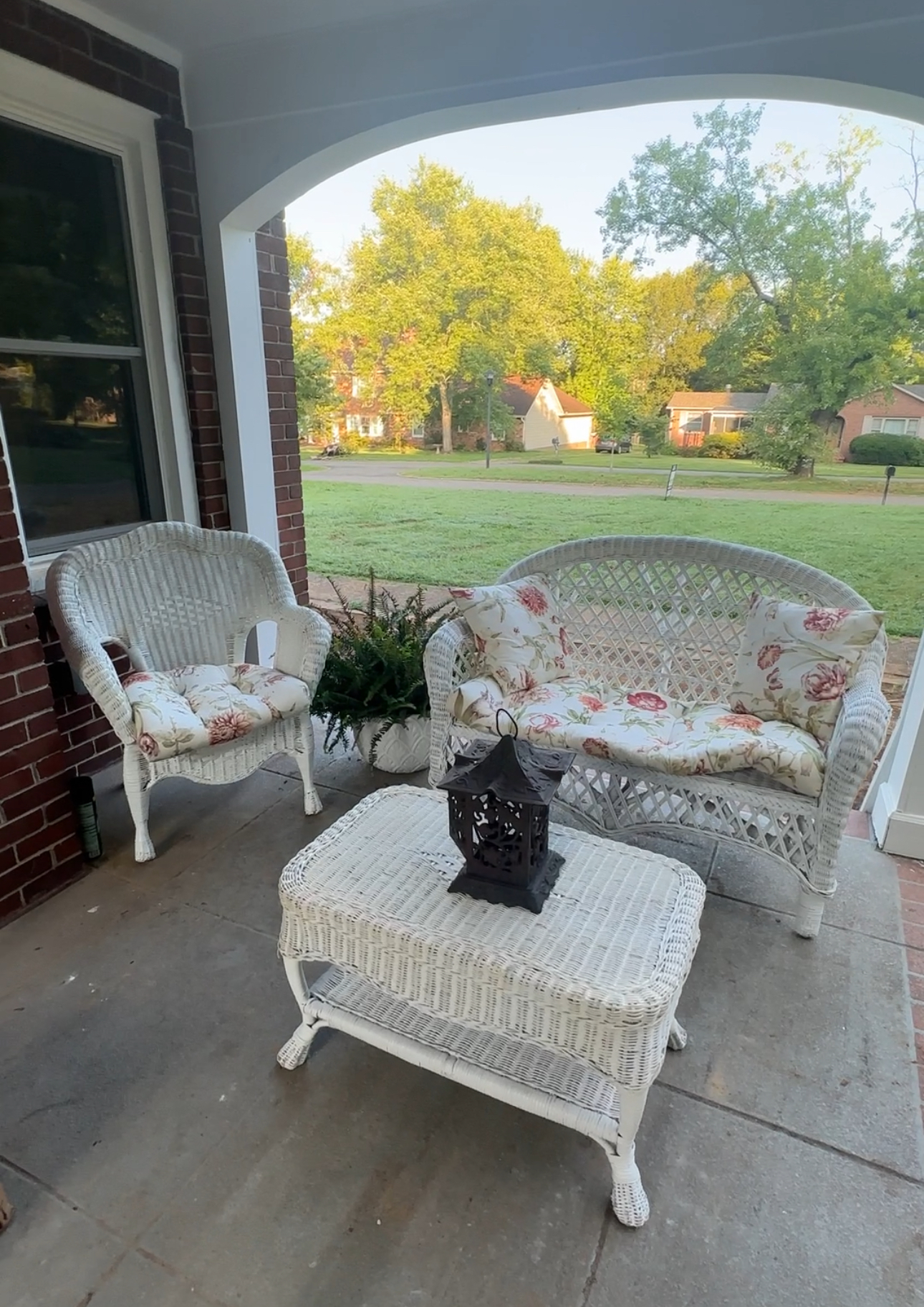 Vintage white wicker settee and chairs arranged on a covered porch