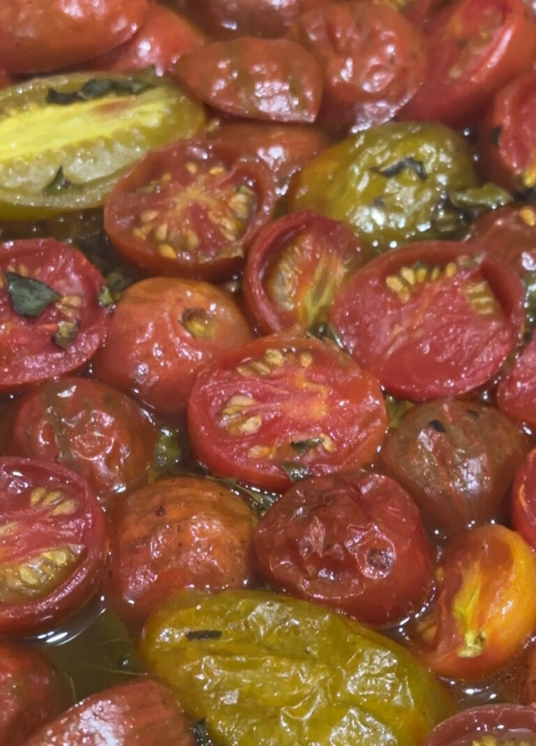 Sliced heirloom tomatoes roasting on a sheet pan