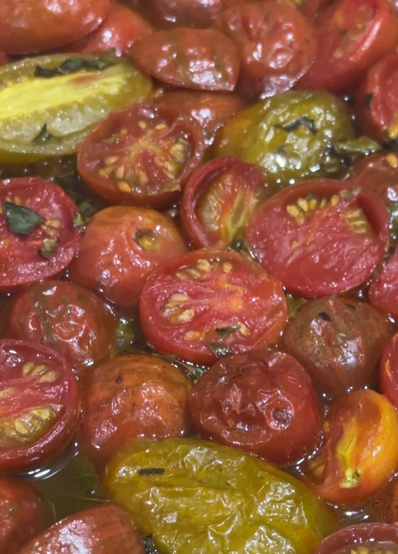 Sliced heirloom tomatoes roasting on a sheet pan