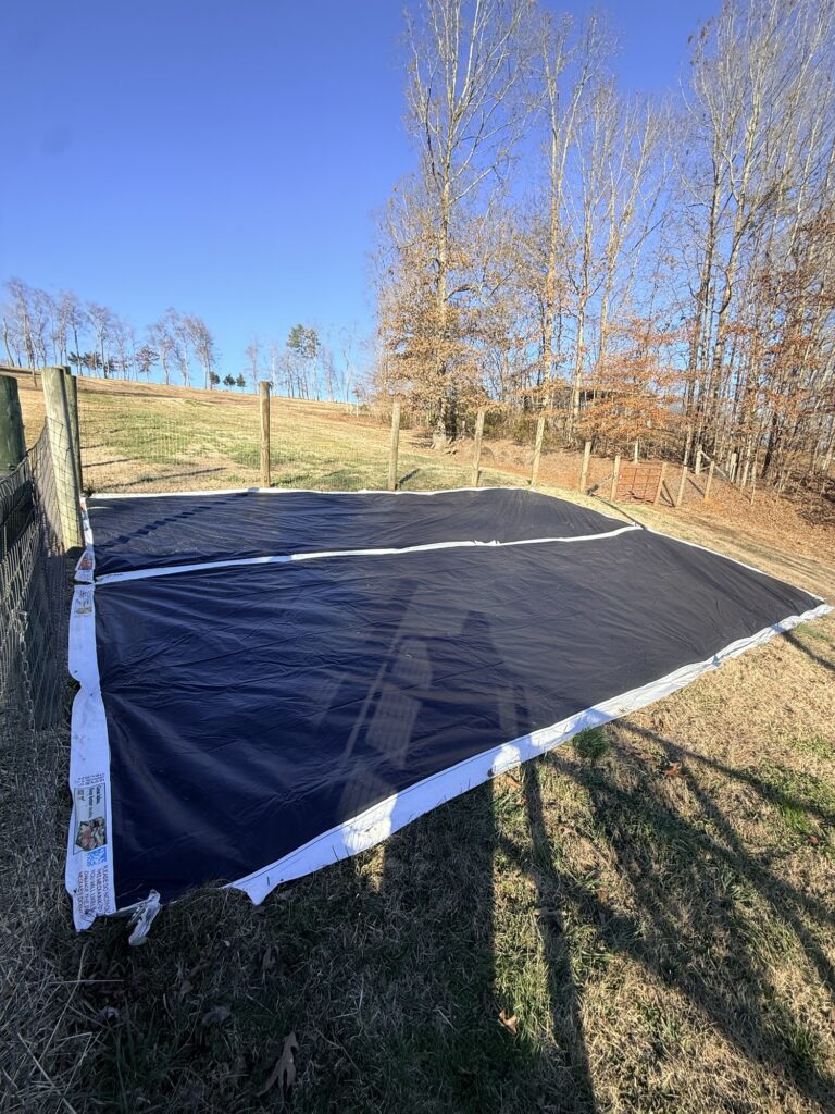 Black tarp laid over a garden area to kill grass through the winter