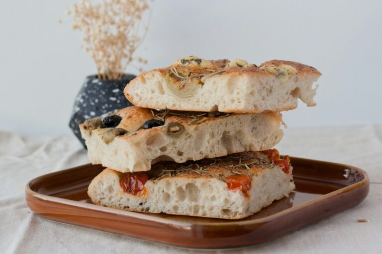 Squares of golden focaccia stacked on a brown plate