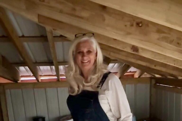 Jules Morris smiling in denim overalls inside the freshly cleaned chicken coop